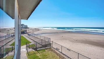 A beach with a concrete structure, a fenced area, and a clear view of the ocean.