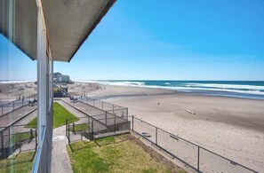 Ein Strand mit einer Betonkonstruktion, einem eingezäunten Bereich und freiem Blick auf das Meer.