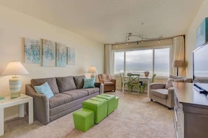 Relax in this inviting living space with a comfortable sofa, green accent chair, and ocean views.