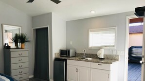 A compact kitchen with white cabinets, a microwave, and a small refrigerator.