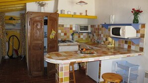 A compact kitchen with a tiled backsplash, a microwave, a stove, and a small bar area. - Small studio with all mod cons and a large shared pool (Lorgues)