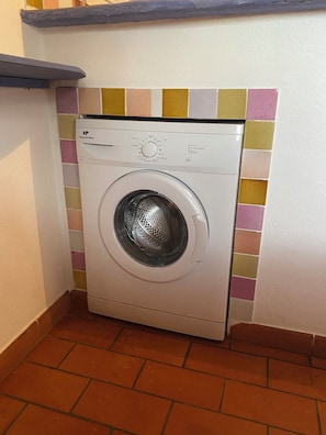 A white washing machine in a corner with a tiled backsplash. - Small studio with all mod cons and a large shared pool (Lorgues)