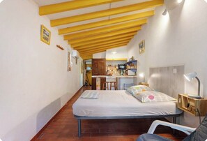 Ein kleines Zimmer mit Bett, Schreibtisch und einer Küchenzeile.