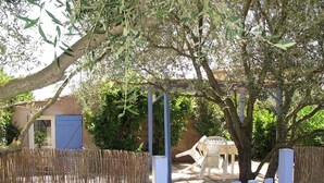 A fenced outdoor area with a table and chairs, a blue door, and a tree providing shade. - Small studio with all mod cons and a large shared pool (Lorgues)