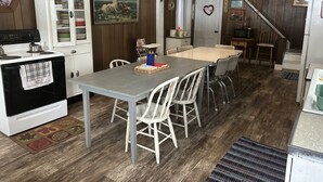 Een keuken met een eettafel, stoelen, een fornuis en een koelkast.