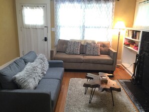 Una sala de estar con un sofá gris, una mesa de centro de madera y una estantería.