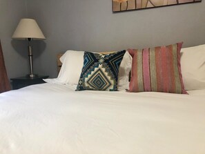 A neatly made bed with white linens, a patterned pillow, and a striped pillow. - Elderberry- Salt Hot Tub, Wood Fireplace, 100+mbps Wifi, Walkable to Downtown (Bend)