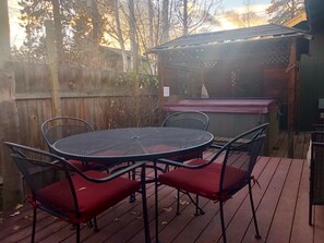 A deck with a round table and chairs, a barbecue grill, and a wooden fence in the background. - Elderberry- Salt Hot Tub, Wood Fireplace, 100+mbps Wifi, Walkable to Downtown (Bend)