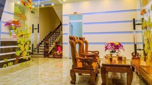 A hotel lobby with a marble floor, wooden furniture, a staircase, and a decorative ceiling.