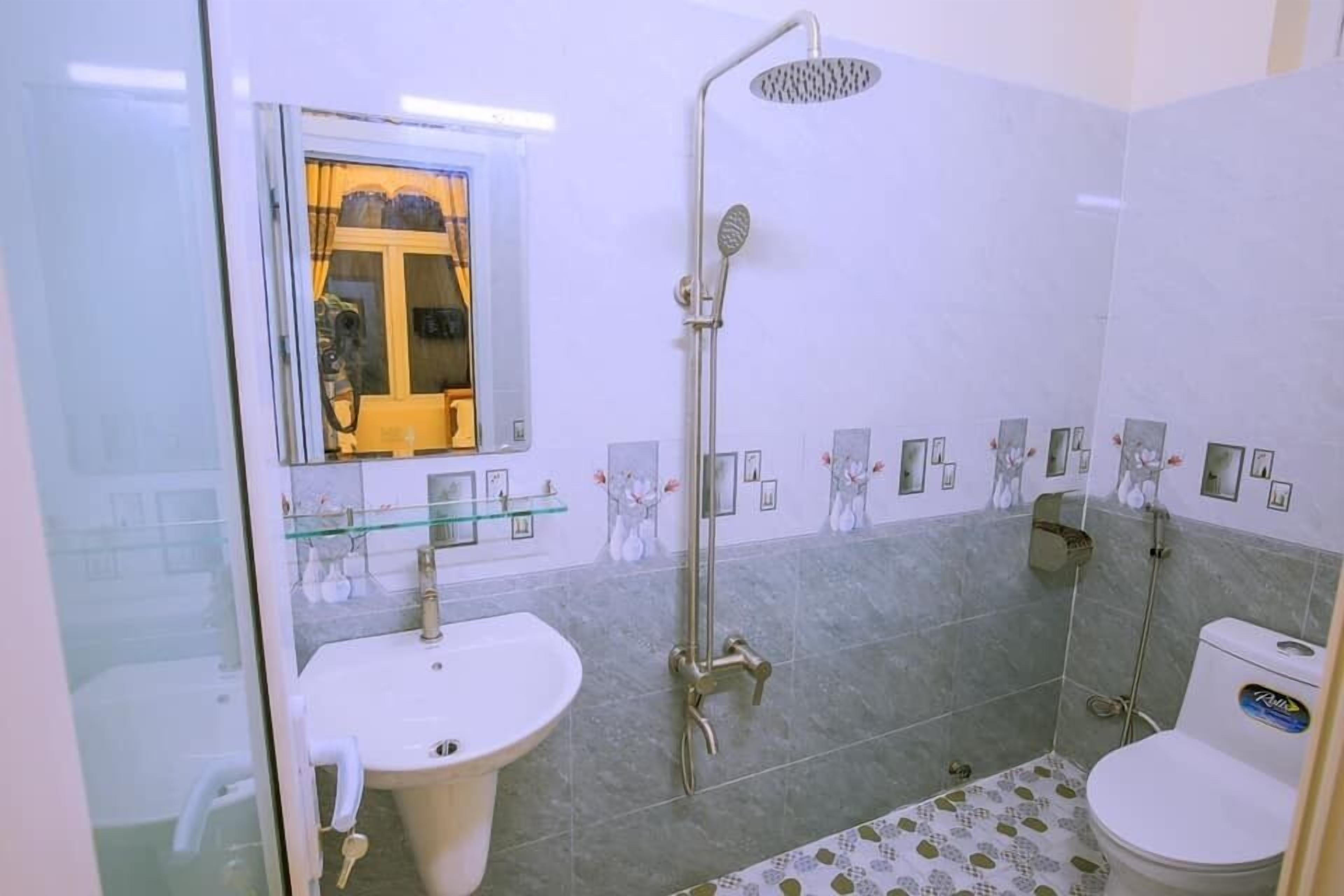 Een badkamer met een glazen douchecabine, een wastafel op een voetstuk en een toilet.