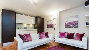 Ein modernes Wohnzimmer mit zwei weißen Sofas, Holzboden und einem violetten Teppich.
