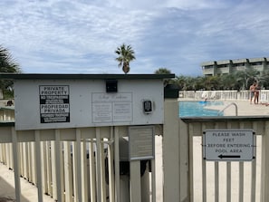 Ein Poolbereich mit Schild, das privates Eigentum und die Poolöffnungszeiten angibt.