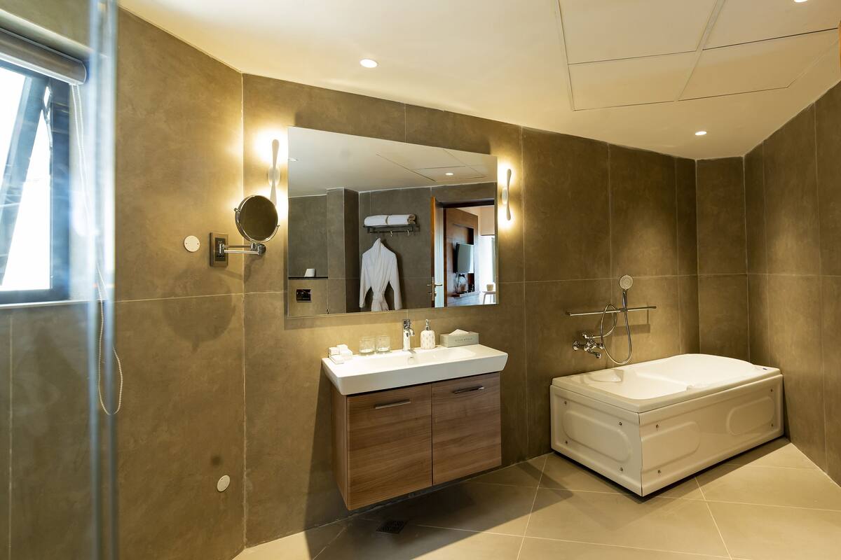 A modern bathroom with a large mirror, a vanity with a sink, and a separate bathtub.