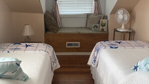 A bedroom with two beds, a window with curtains, a bedside table with a lamp, and a standing fan. - BEAUTIFUL PEACEFUL, SCENIC, ENJOY CRABS N FISH MEMORABLE, FREE TOUR OF AREA! (Fishing Creek)