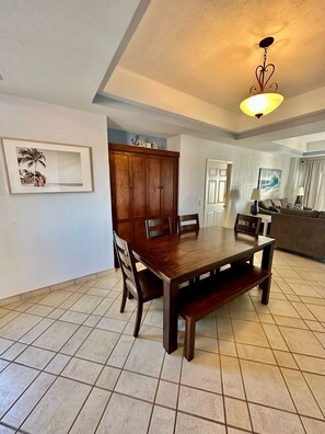 A dining area with a wooden table and chairs, a cabinet, and a ceiling light fixture.