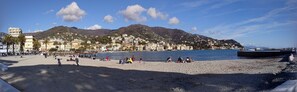 Une plage où des gens se détendent, un ciel dégagé et des bâtiments en arrière-plan.