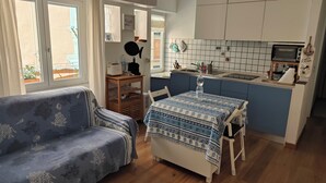 Ett kompakt bostadsutrymme med en soffa, ett matbord och ett litet kök.
