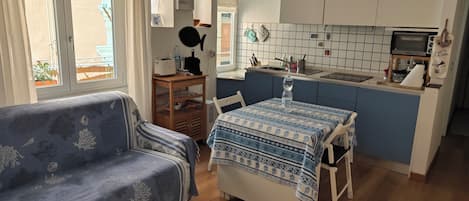 A compact living space with a sofa, a dining table, and a kitchenette.