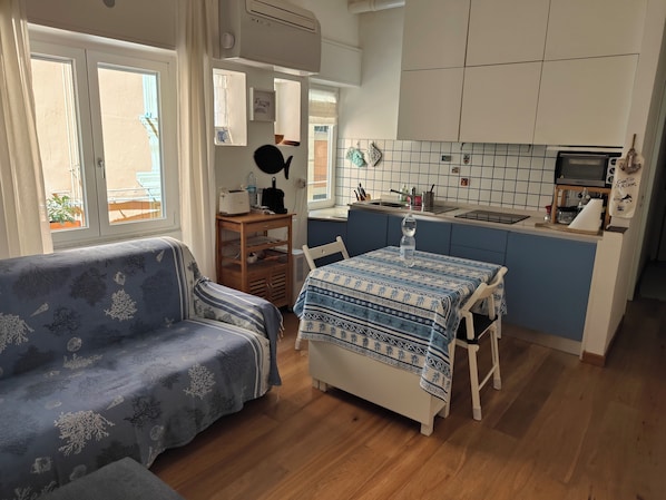 A compact living space with a sofa, a dining table, and a kitchenette.