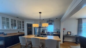 Une cuisine moderne dotée d’un îlot central, de tabourets de bar et de luminaires suspendus.