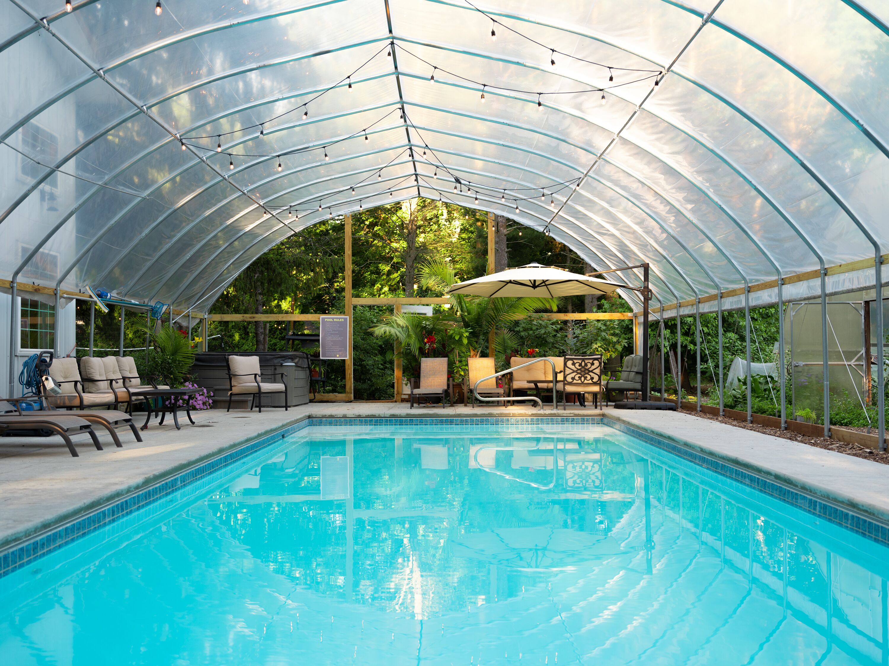 A covered pool area with seating and a sign indicating 'Pool Rules'.
