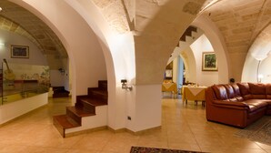 A spacious interior with a staircase, a leather sofa, and a dining area.