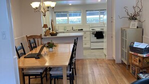 A modern kitchen with white cabinets, a wooden dining table, and a chandelier.