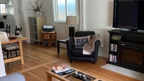 A living room with a sofa, a coffee table, a television, and a fireplace.