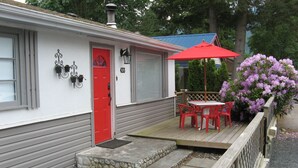 A house with a red door, a deck with red chairs, and a red umbrella.