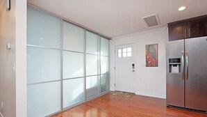 Una cocina moderna con un refrigerador de acero inoxidable, una puerta corredera de vidrio y una alfombra pequeña.