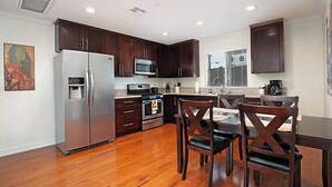 Una cocina moderna con armarios de madera oscura, electrodomésticos de acero inoxidable y una mesa de comedor de madera con sillas.