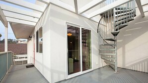 Un edificio moderno con puerta de entrada de vidrio, un patio cubierto y una escalera de caracol.