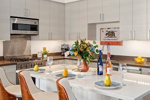 A modern kitchen with stainless steel appliances, a central island with seating, and a California Republic sign. - Stylish Studio Apartment in the Heart of Downtown Santa Barbara! (Santa Barbara)