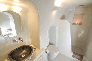 Un bagno con lavabo in pietra, un water e uno specchio.