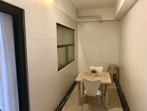 Ein schmaler Flur mit kleinem Tisch, Stuhl, Fenster und Tür.