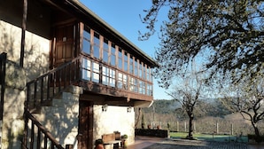 A two-story building with a balcony, stone steps, and a paved courtyard.