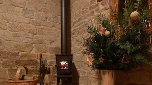 A stone-walled room with a fireplace, a Christmas tree, and a woven basket.
