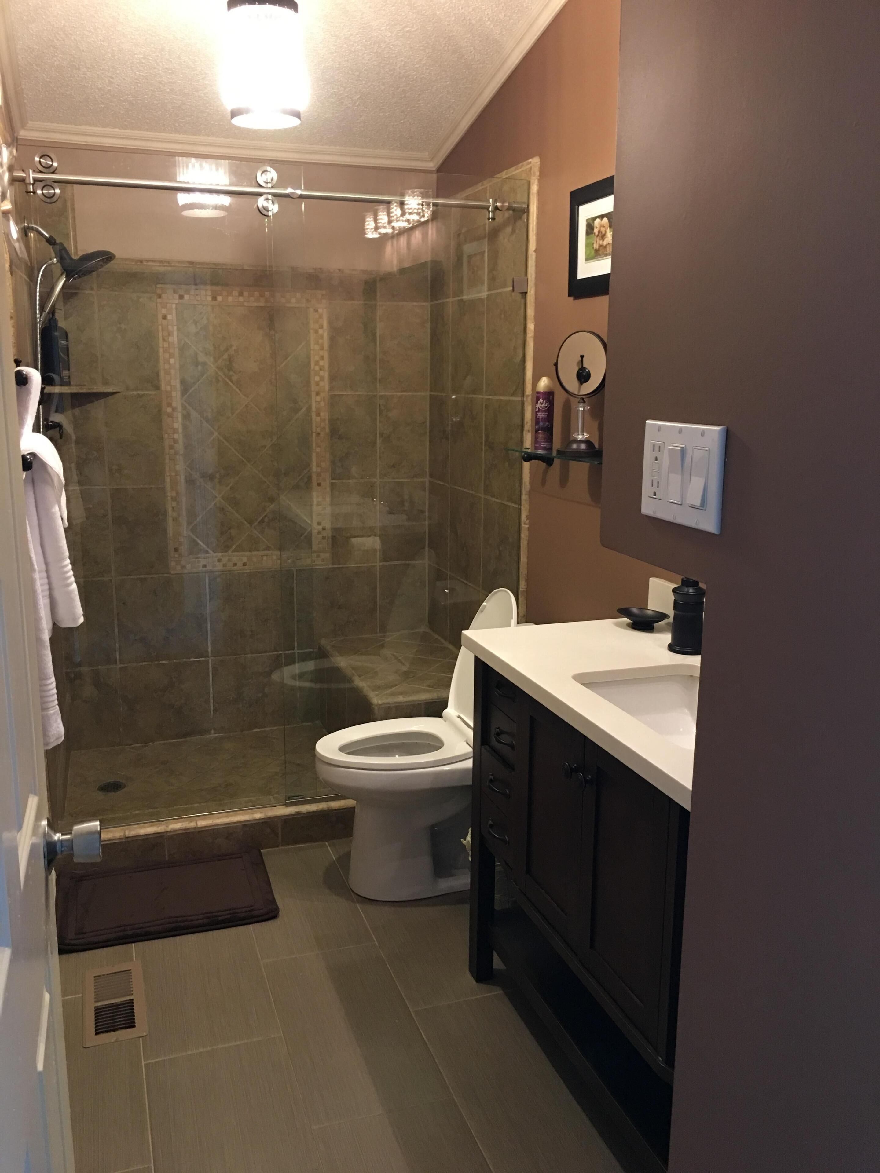 Un baño con ducha de vidrio, inodoro, lavabo y espejo.