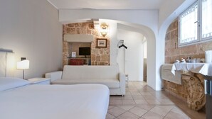 Une chambre d’hôtel dotée d’un grand lit, d’un canapé, d’un mur décoratif en pierre, d’une cheminée et d’un coin cuisine avec un évier et un plan de travail.