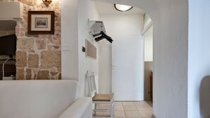 Un couloir avec un mur en pierre, une porte blanche et une chaise blanche.