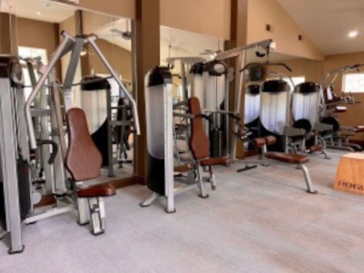 Uma academia com diversos equipamentos de exercício, incluindo bancos de peso e aparelhos de cardio.