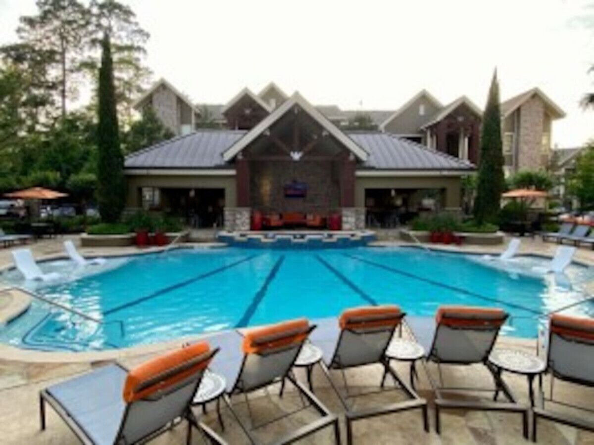 A swimming pool with lounge chairs and a building in the background.