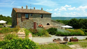 Un bâtiment en pierre avec un toit recouvert de tuiles, une petite fenêtre et une cheminée.