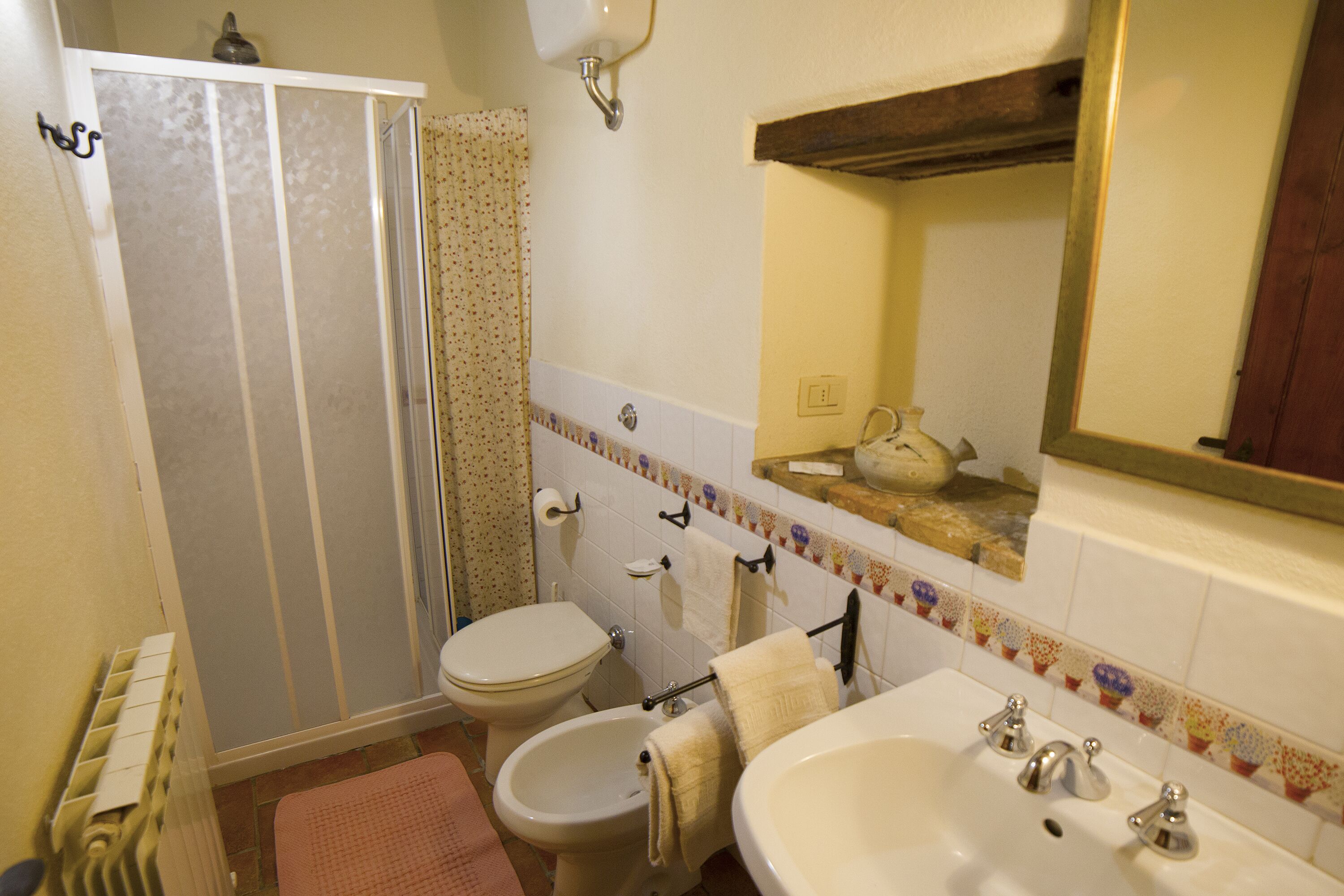 Une salle de bain équipée d’une douche, de toilettes, d’un bidet, d’un lavabo et d’un miroir.