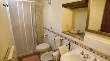 Une salle de bain équipée d’une douche, de toilettes, d’un bidet, d’un lavabo et d’un miroir.