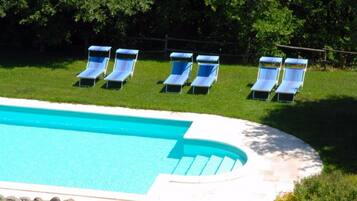 Une piscine à bord incurvé, entourée d’une pelouse et d’arbres.