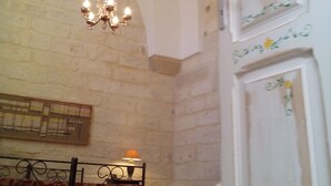 A room with a stone wall, a chandelier, a bed with a floral bedspread, and a white door with floral decorations.