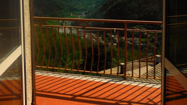 Un balcone con ringhiera in metallo che si affaccia su una valle montana.