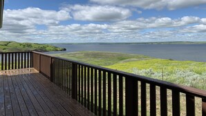 Une terrasse en bois offrant une vue sur un lac et des collines lointaines.