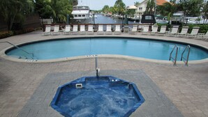 Una piscina amb un banyera d'hidromassatge al primer pla, envoltada de gandules i un port esportiu al fons.